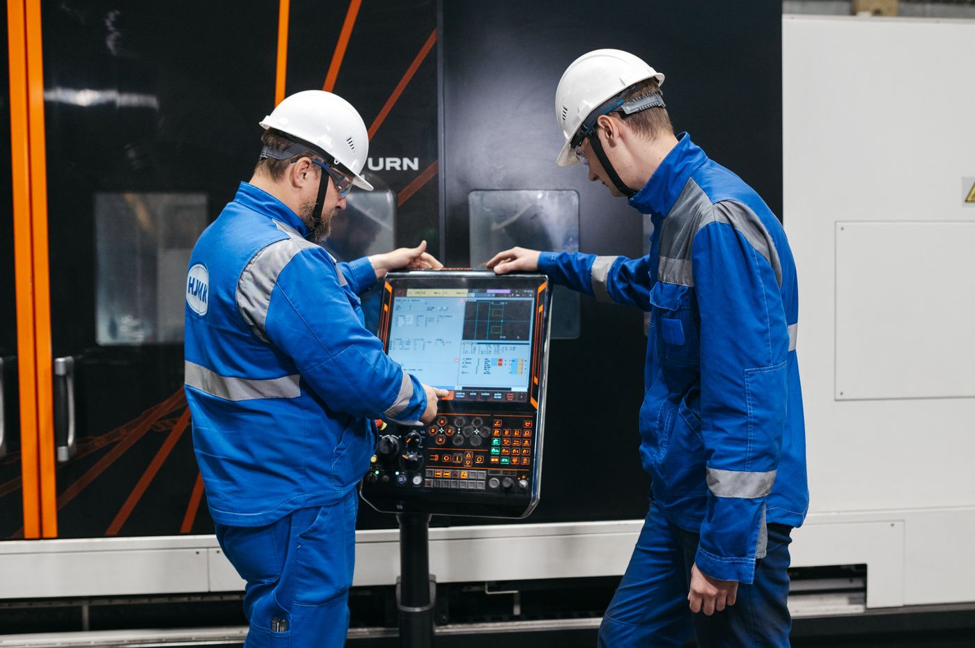 Zwei Fachkräfte bedienen gemeinsam eine CNC-Maschine